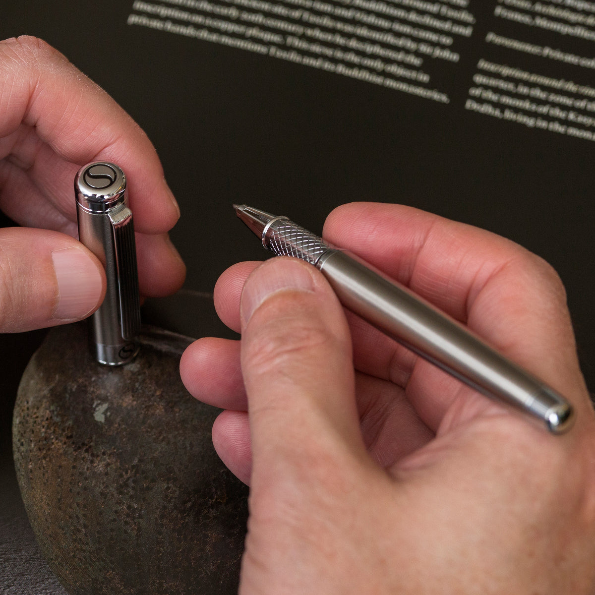 Close-up of hands holding a metallic tool against a dark background with text.